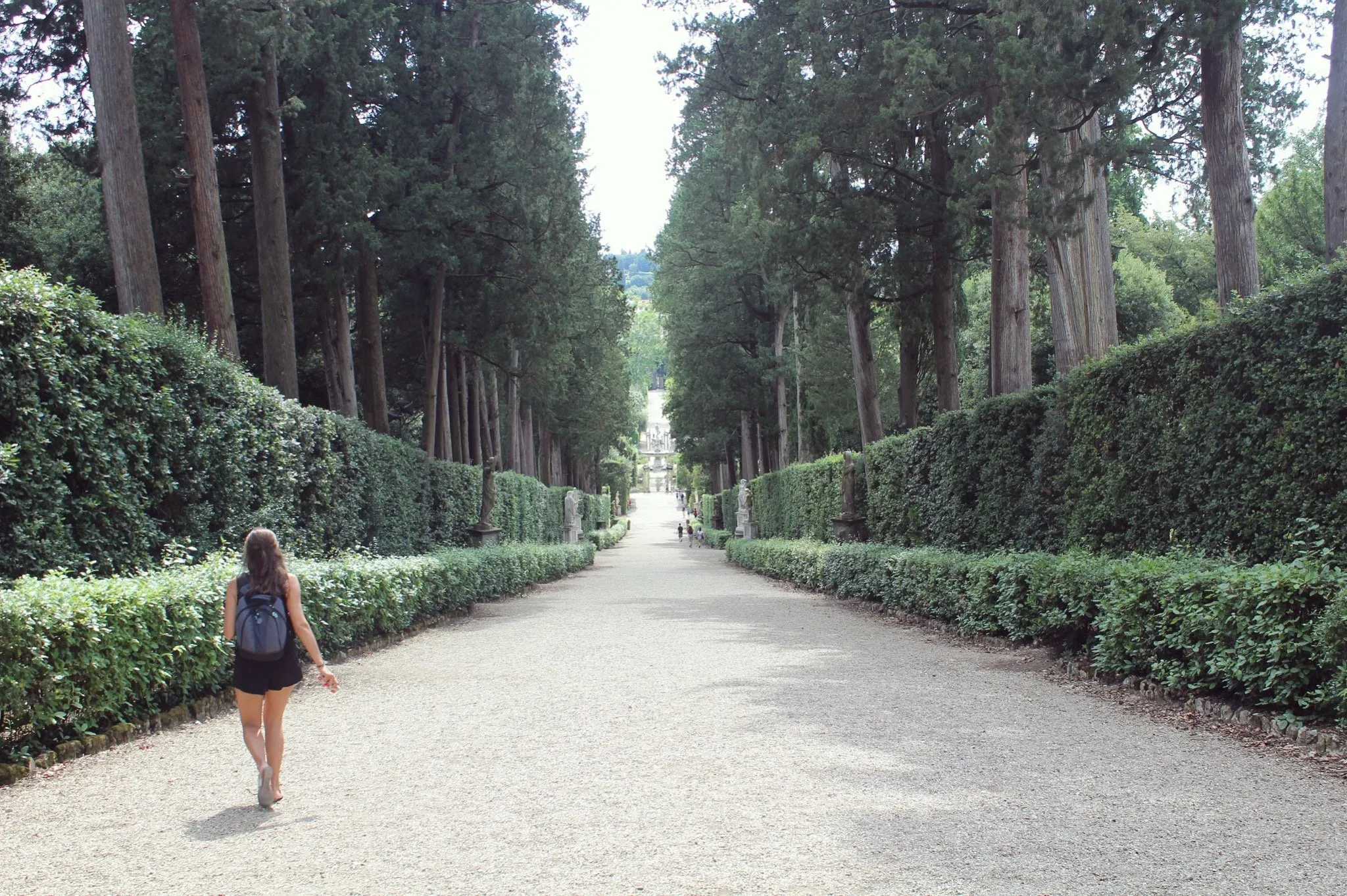 A wide gravel path, someone with a backpack walking away.