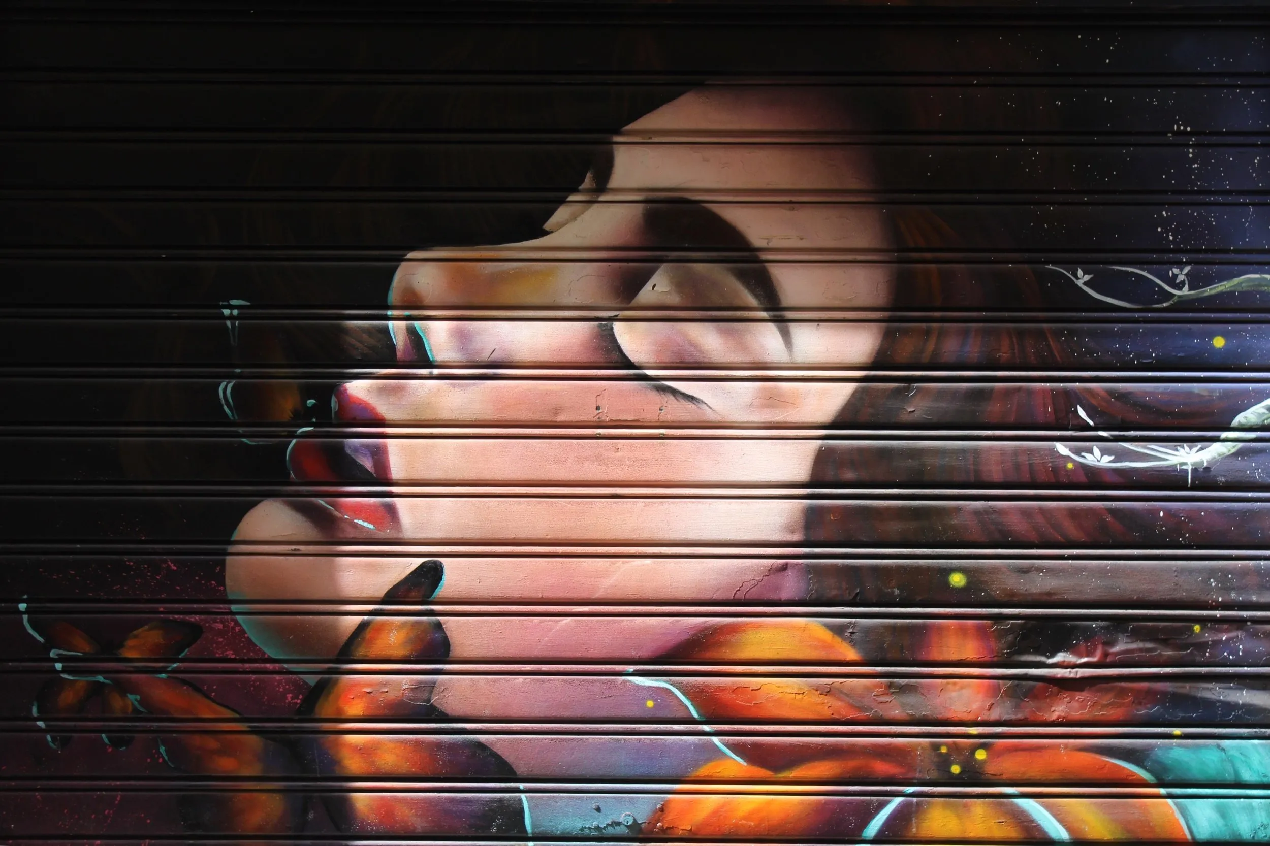 A painted shutter: a woman with red hair, eyes closed, surrounded by stars.